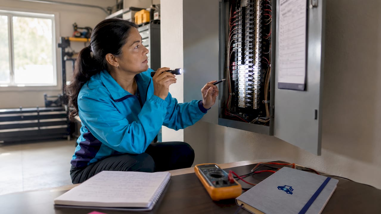 Hands inspecting home electrical panel circuits