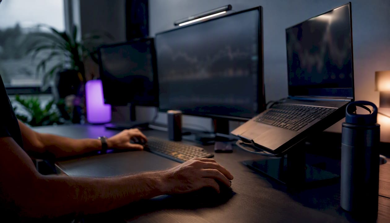 Hands poised over dark multi-monitor crypto trading setup