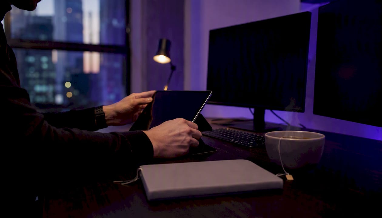 Trader hands adjusting tablet on trading desk