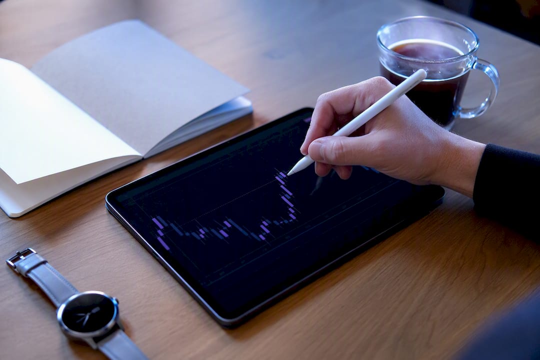 Hand with stylus near stock chart on desk