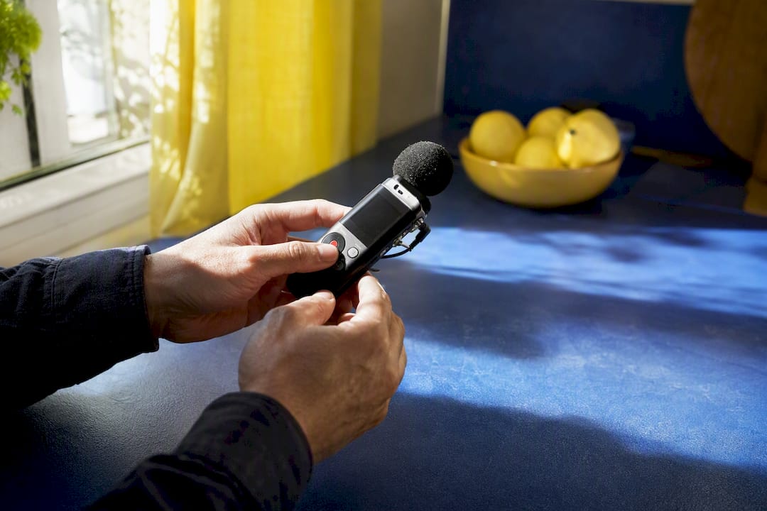 Hands holding voice recorder over desk