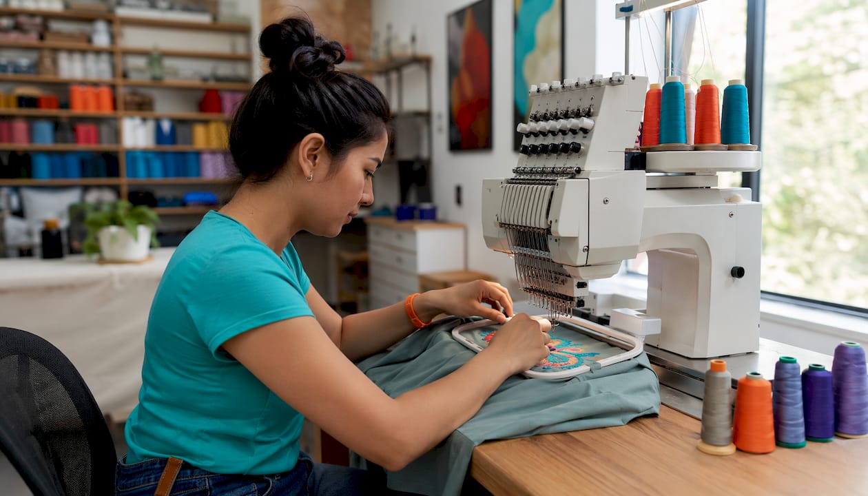 Hands stitching colorful threads on fabric patch