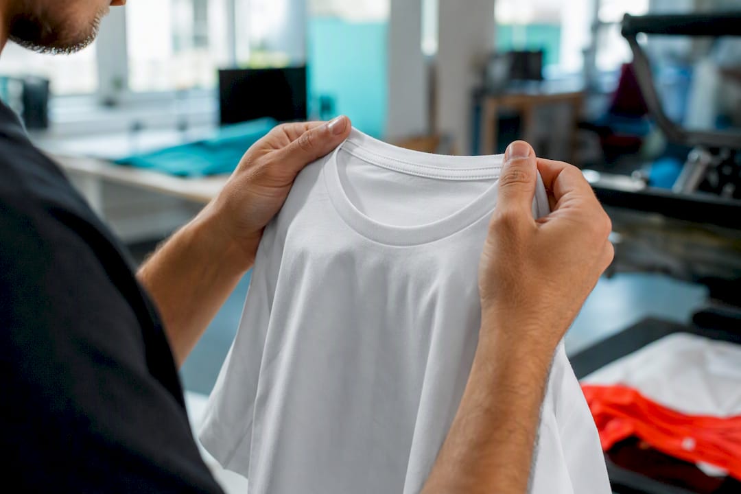 Hands inspecting custom T-shirt fabric quality