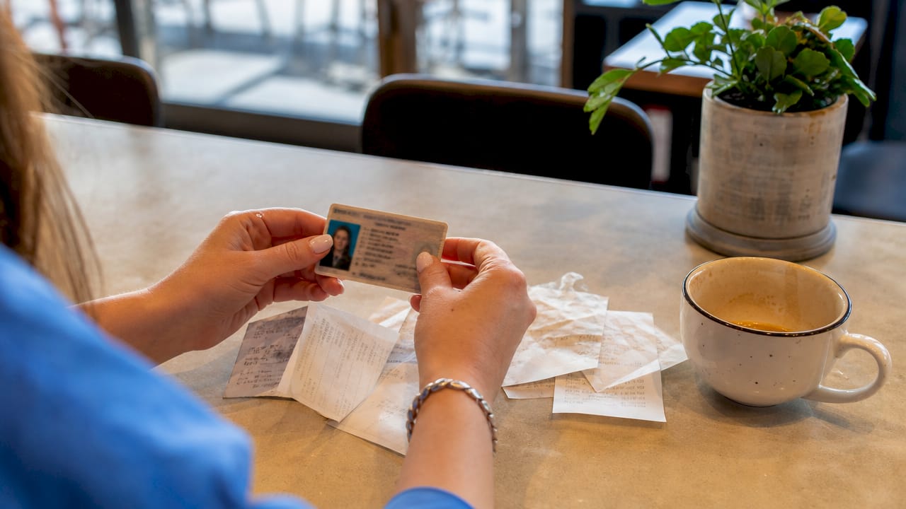 Close-up of hands holding photo ID over documents