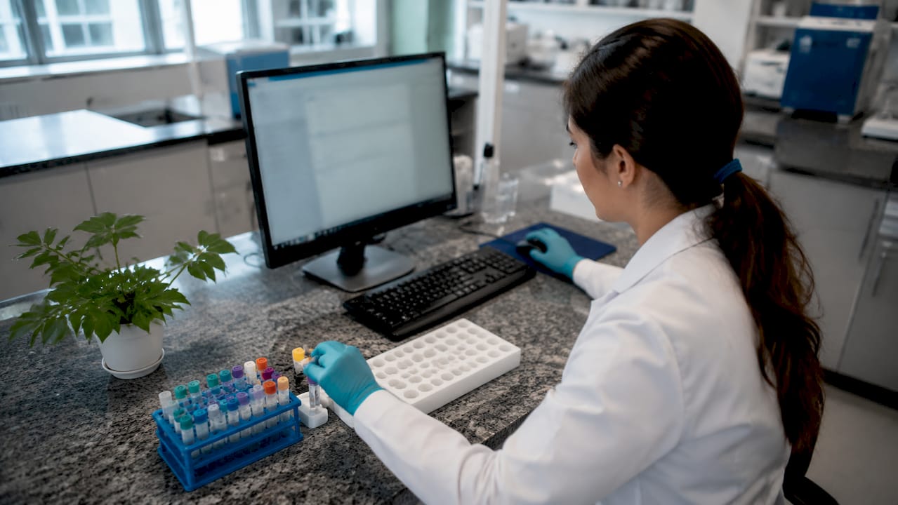 Lab technician logging DNA sample tube indoors