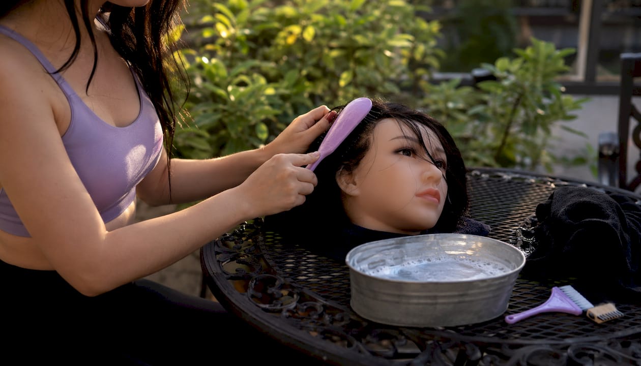 Hands brushing implanted hair on silicone doll