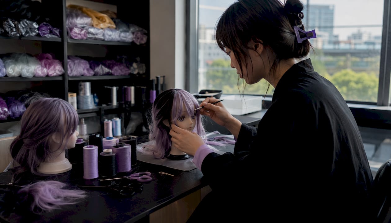 Doll maker styling anime-style doll hair at workbench