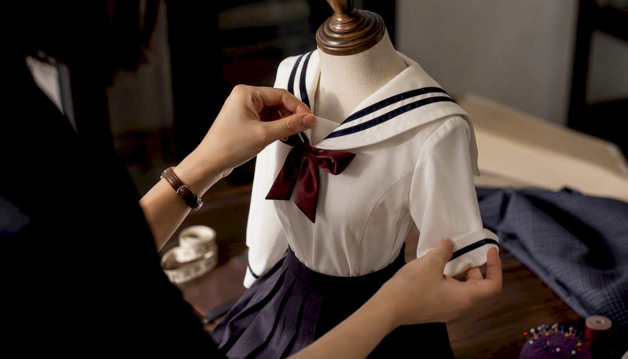 Hands tailoring schoolgirl doll uniform fabric