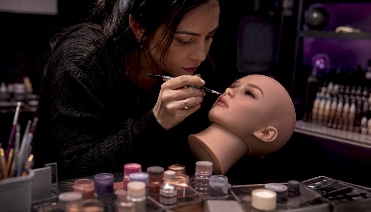Artist applying custom makeup to silicone doll face