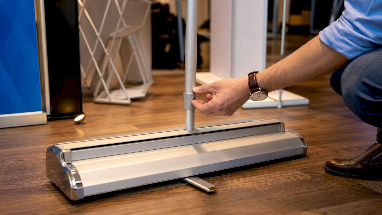 Close-up of banner stand base with hand adjusting pole