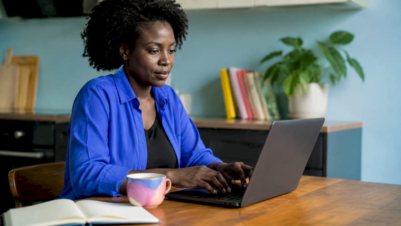 Iemand zit achter een laptop te typen, terwijl het Azure Portal open staat op het scherm als handige referentie.