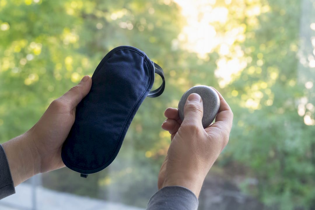 Hands holding sleep mask and stress relief stone