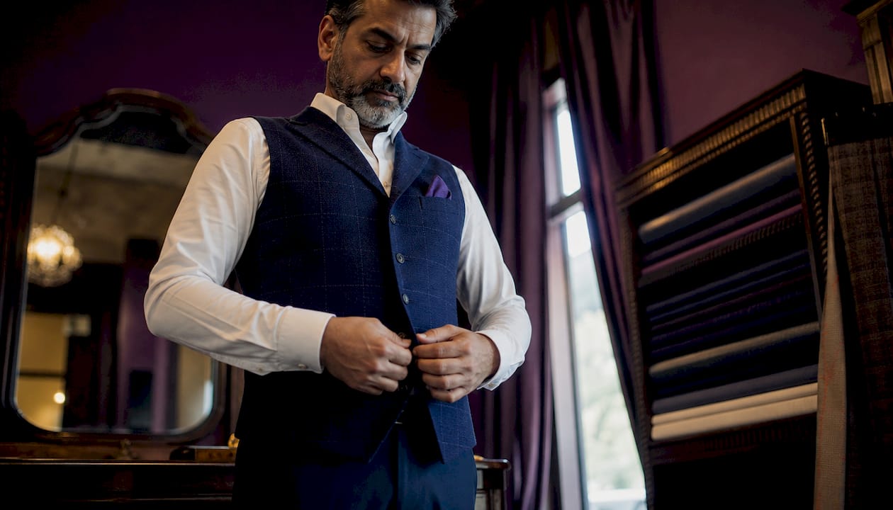 Man checking fit of tailored vest in tailor shop