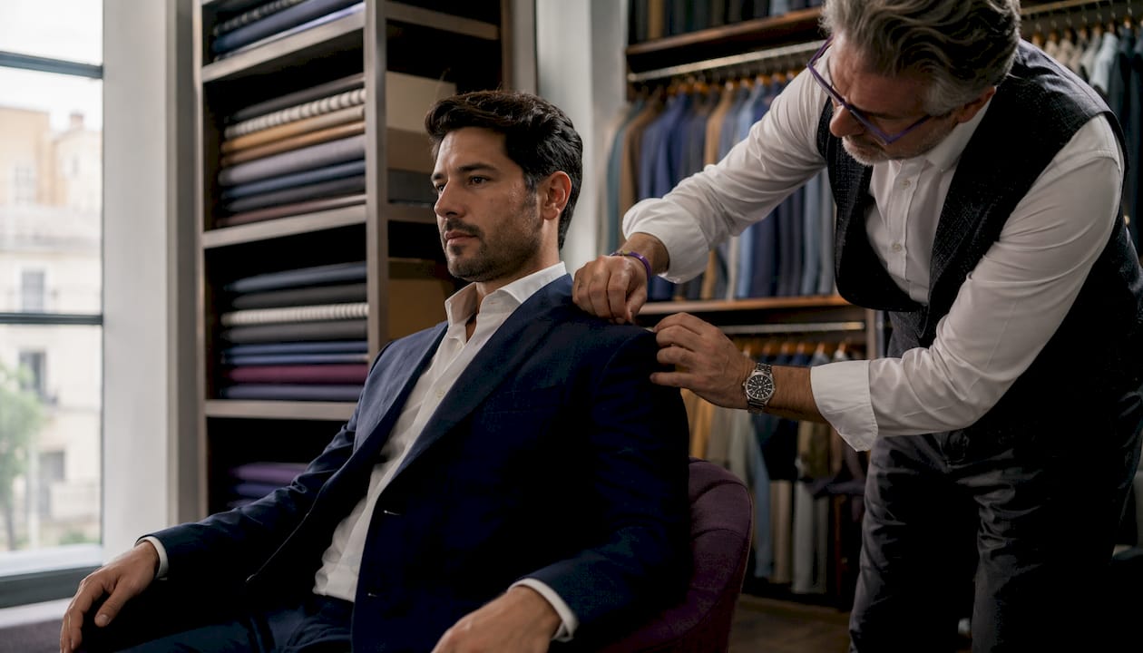 Tailor fitting suit jacket shoulder seam on client