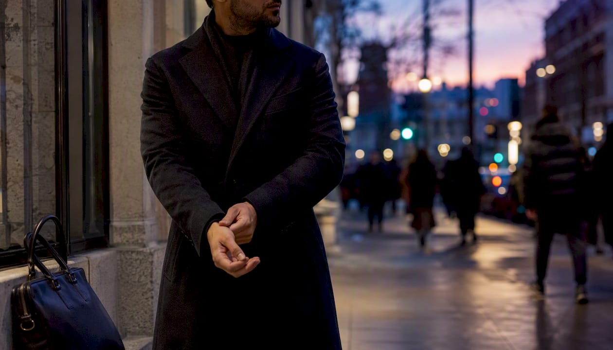 Man adjusting wool coat cuff on city street