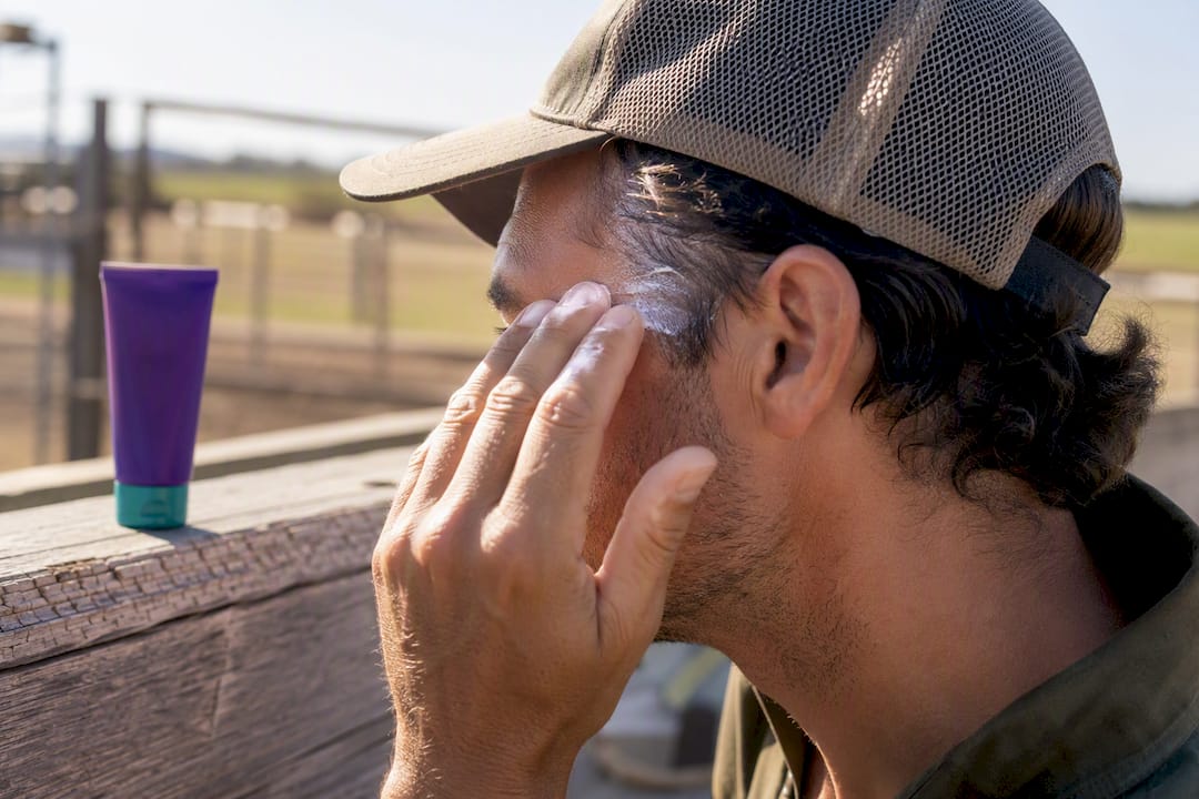 Applying sunscreen beneath a mesh cap
