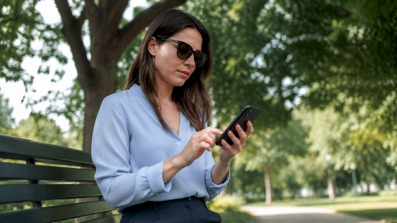 Woman submitting crash report on smartphone outdoors