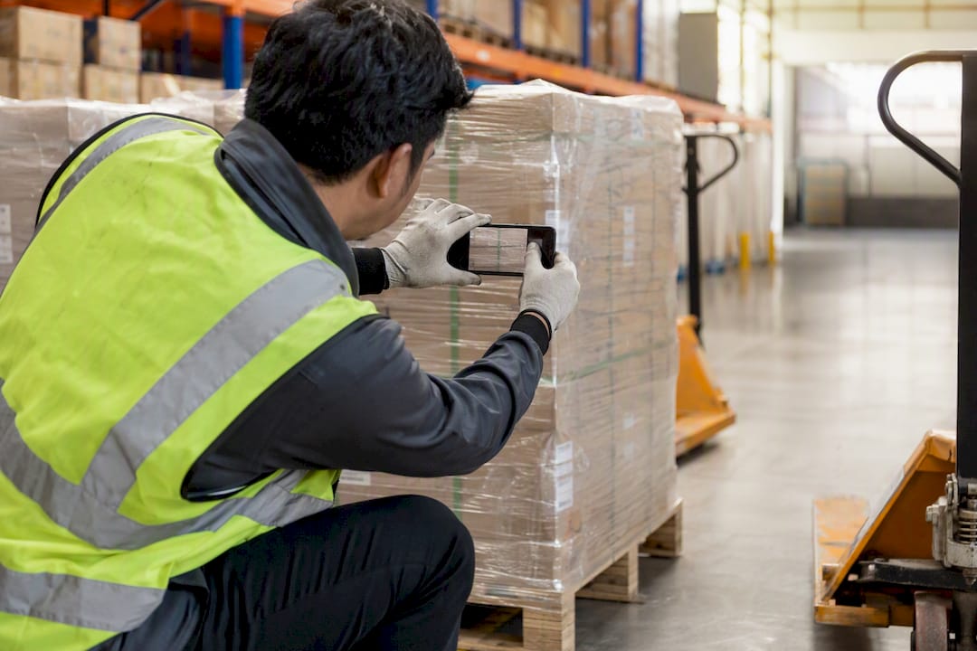 Worker photographing pallet labels for verification