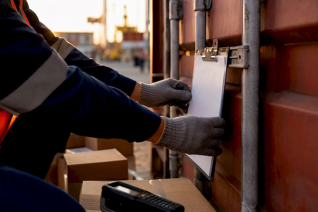 Hands attaching checklist to shipping container