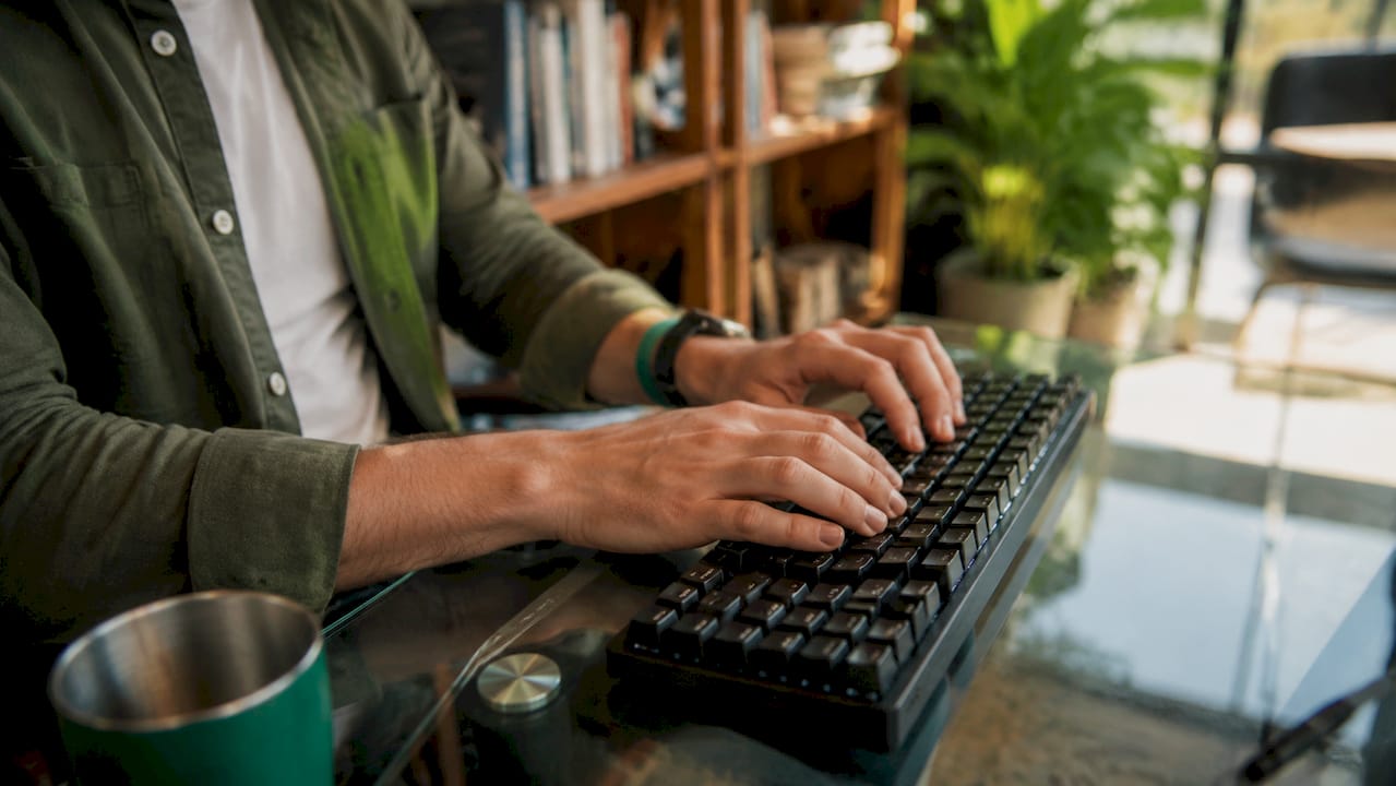 Dita che scorrono rapide sulla tastiera in un ambiente di lavoro professionale.