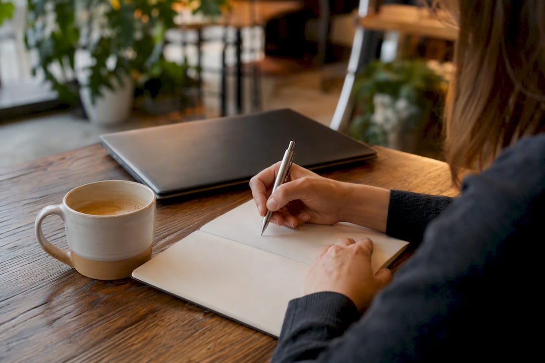 Hands writing quantified achievement on desk