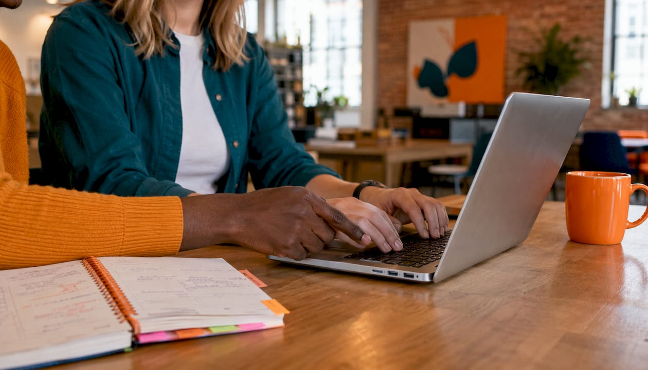 Hands typing on laptop in marketing workspace