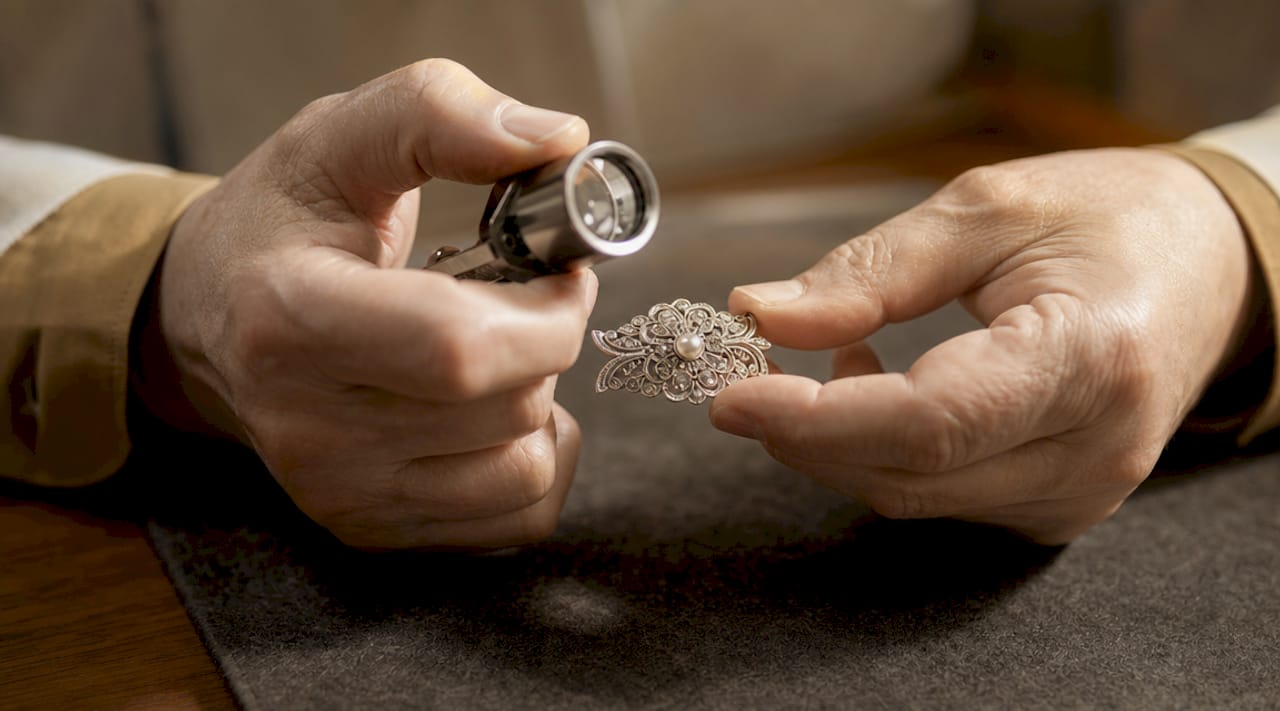 Close-up hands inspecting gold pendant details