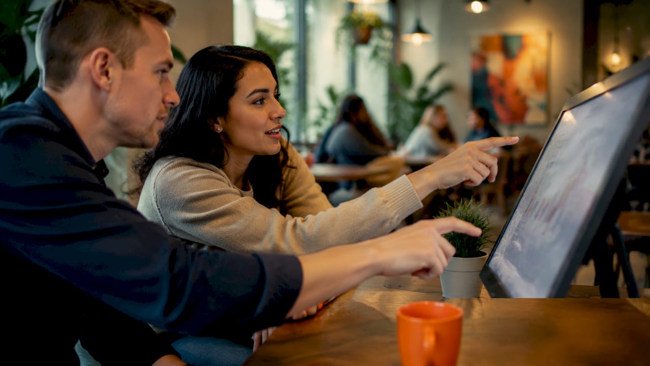 Hands pointing at digital data dashboard in office