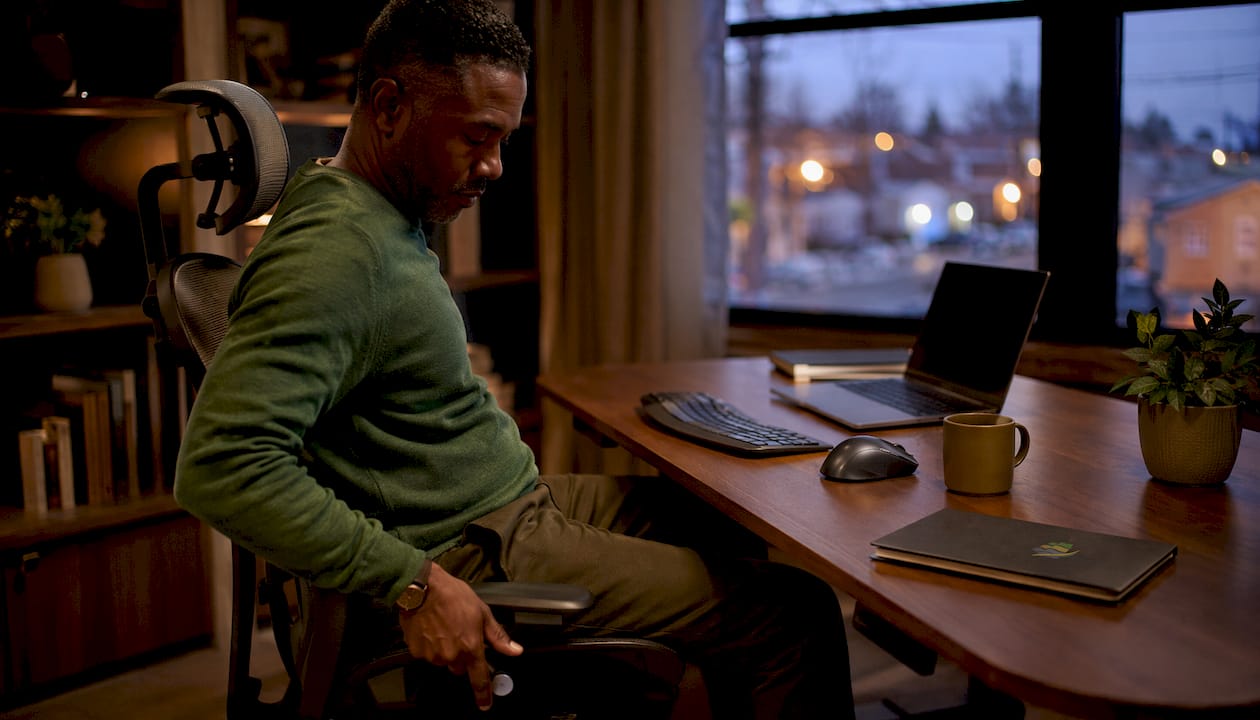Man adjusting ergonomic chair in home office