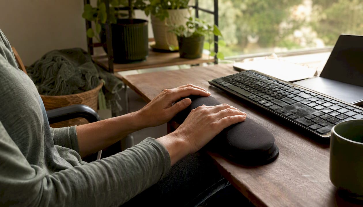 Hands resting briefly on wrist rest at desk
