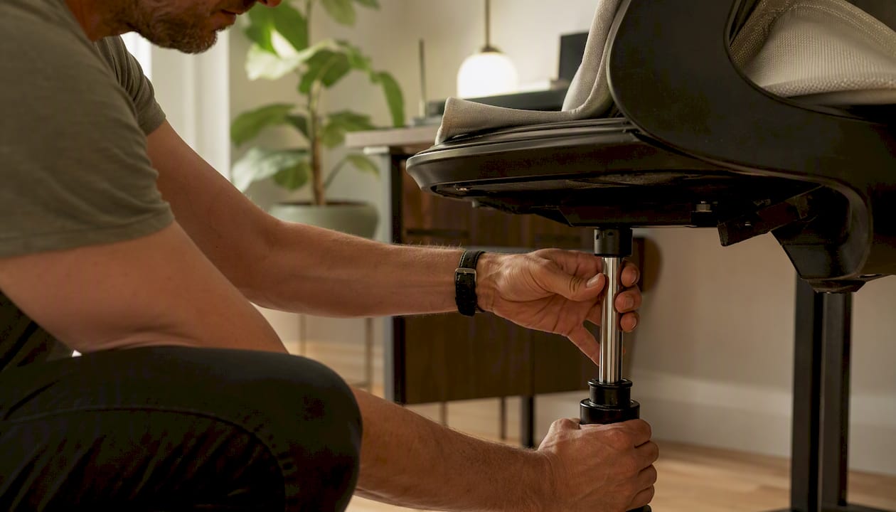 Hands replacing ergonomic chair gas cylinder part