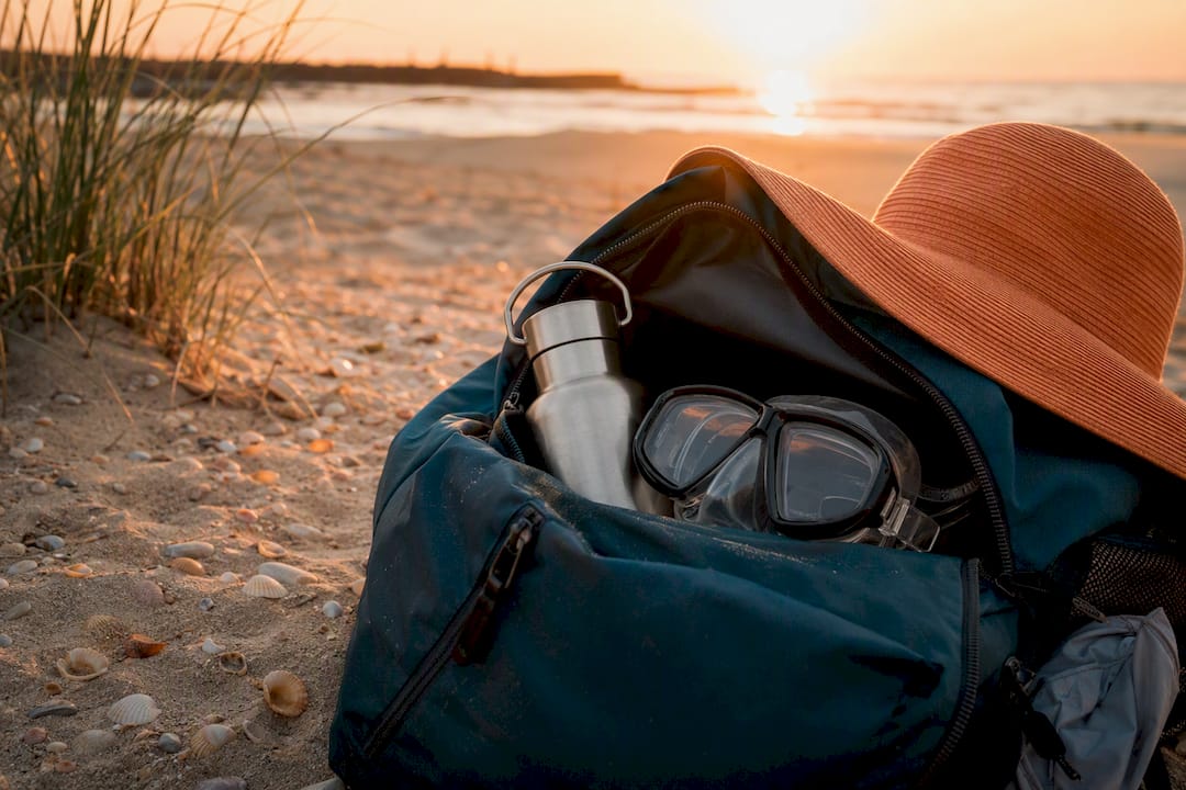 Backpack with snorkel and sun hat on coastal rocks
