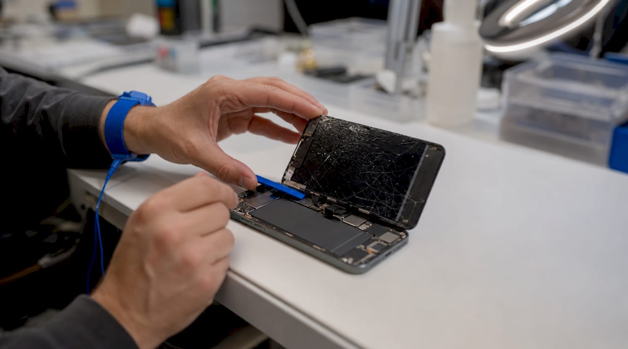 Close-up of hands removing iPhone screen components