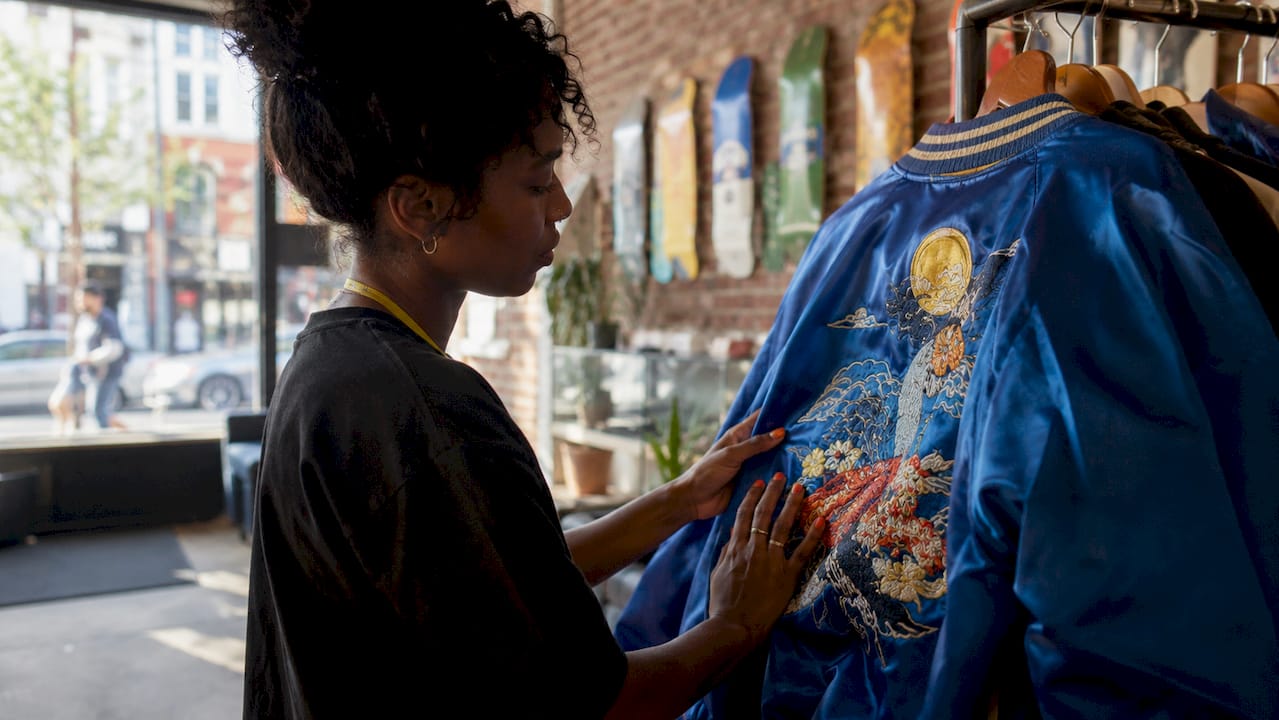Hands inspecting embroidered custom jacket in store
