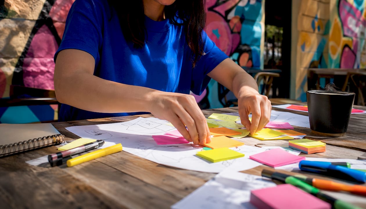Hands writing sticky notes brainstorming