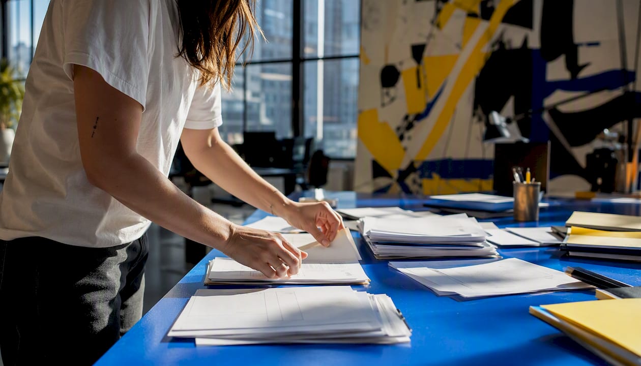 Hands organizing production call sheets in office