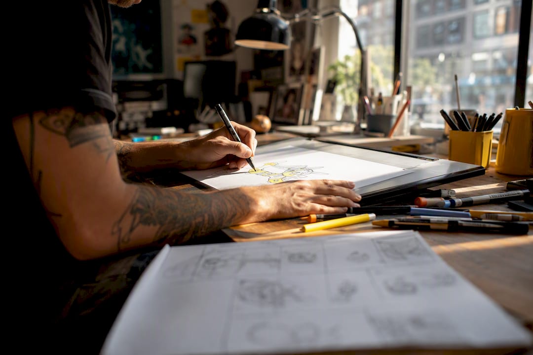 Hands sketching animation frames on light pad