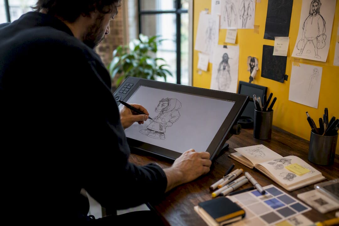 Hands creating custom character design on tablet
