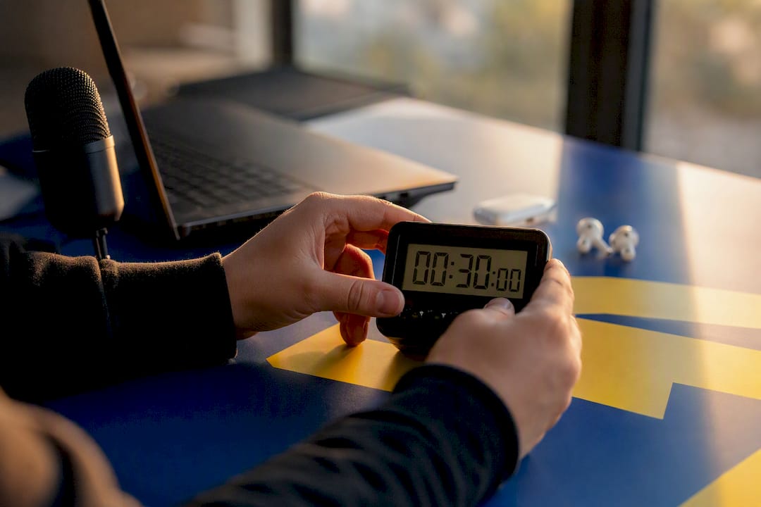 Hands setting countdown timer on desk