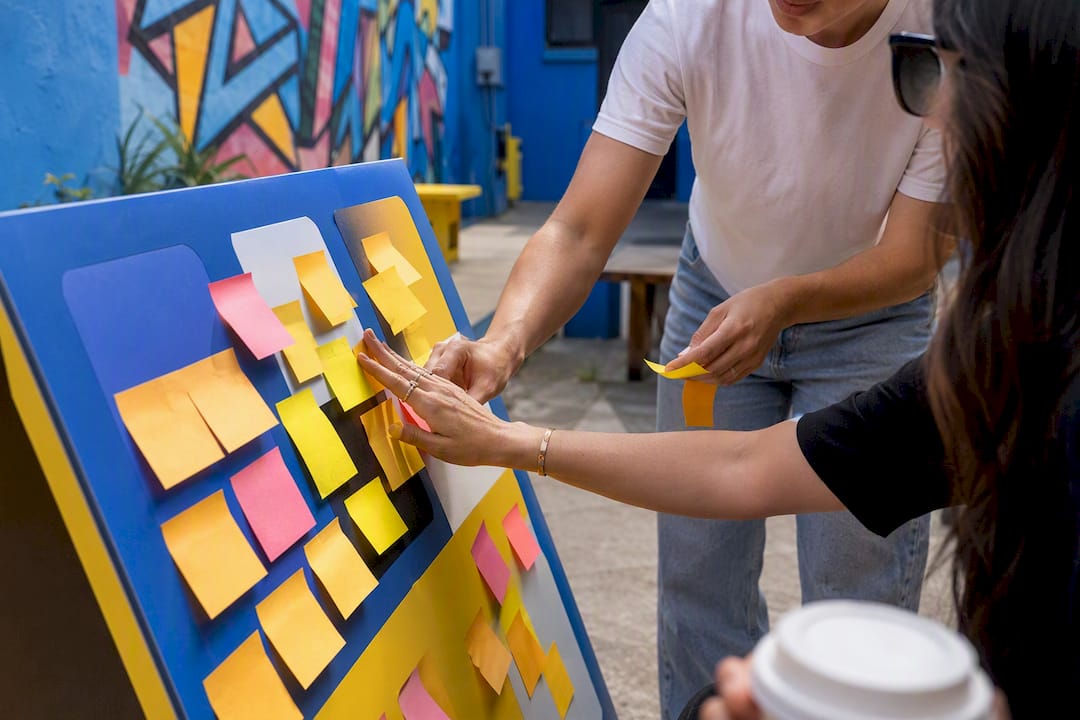 Hands placing risk category sticky notes on glass wall
