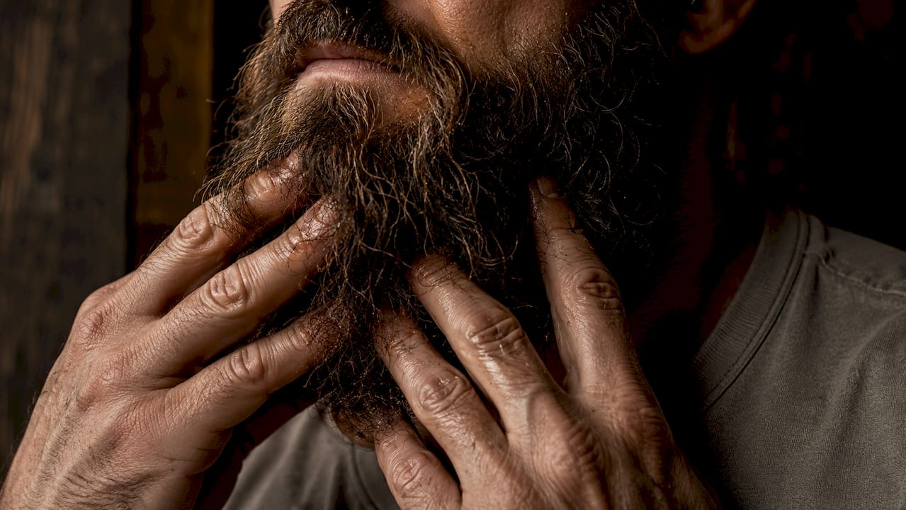 Close-up of coarse beard hair with hands applying serum