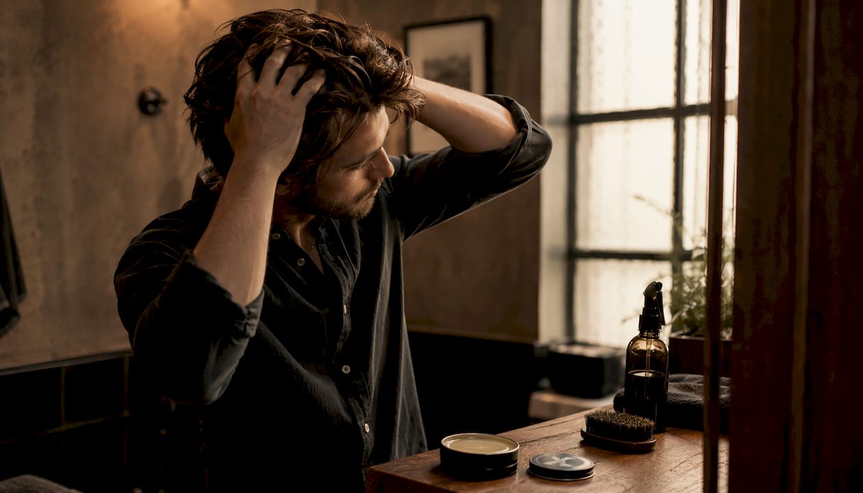 Hands styling hair with light pomade