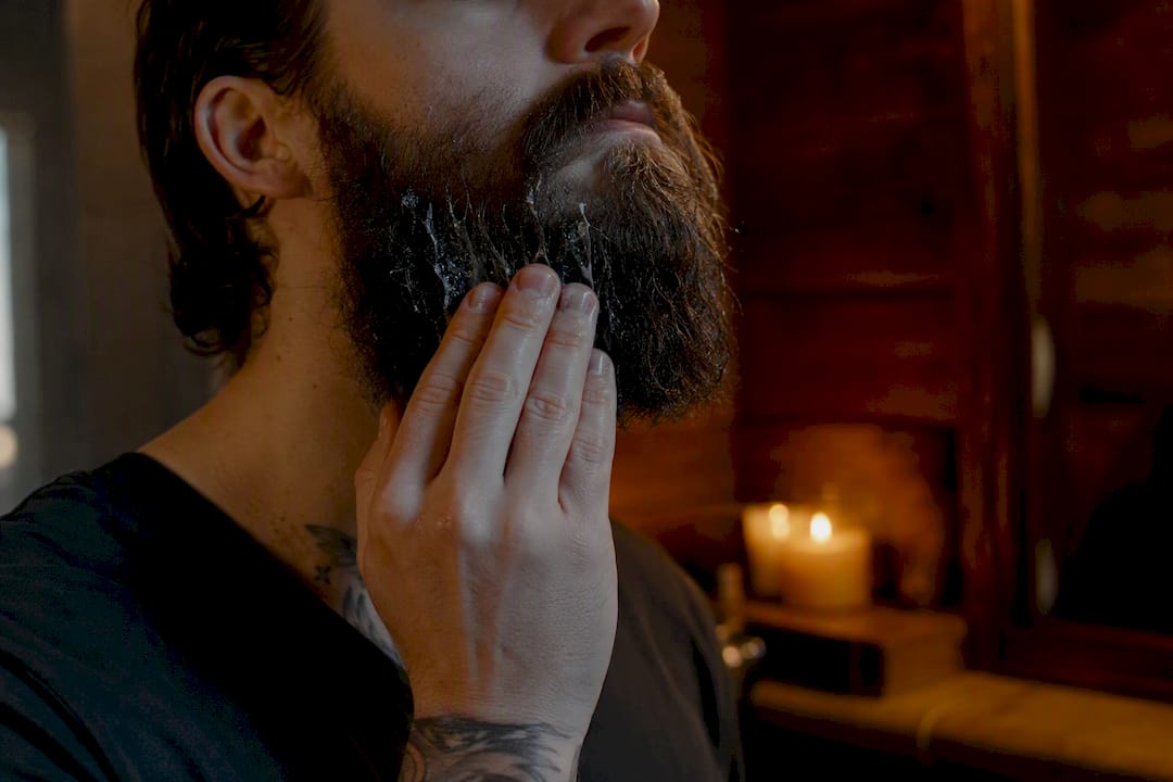 Hand applying conditioner to coarse beard