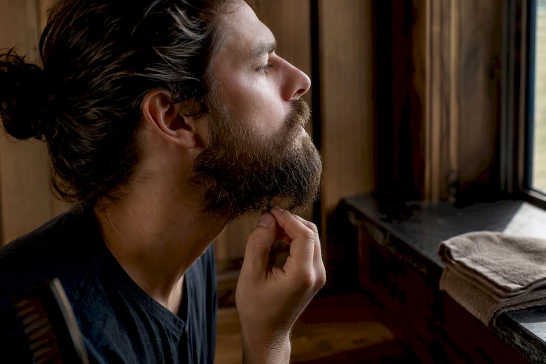 Man gently stopping at a stubborn beard knot