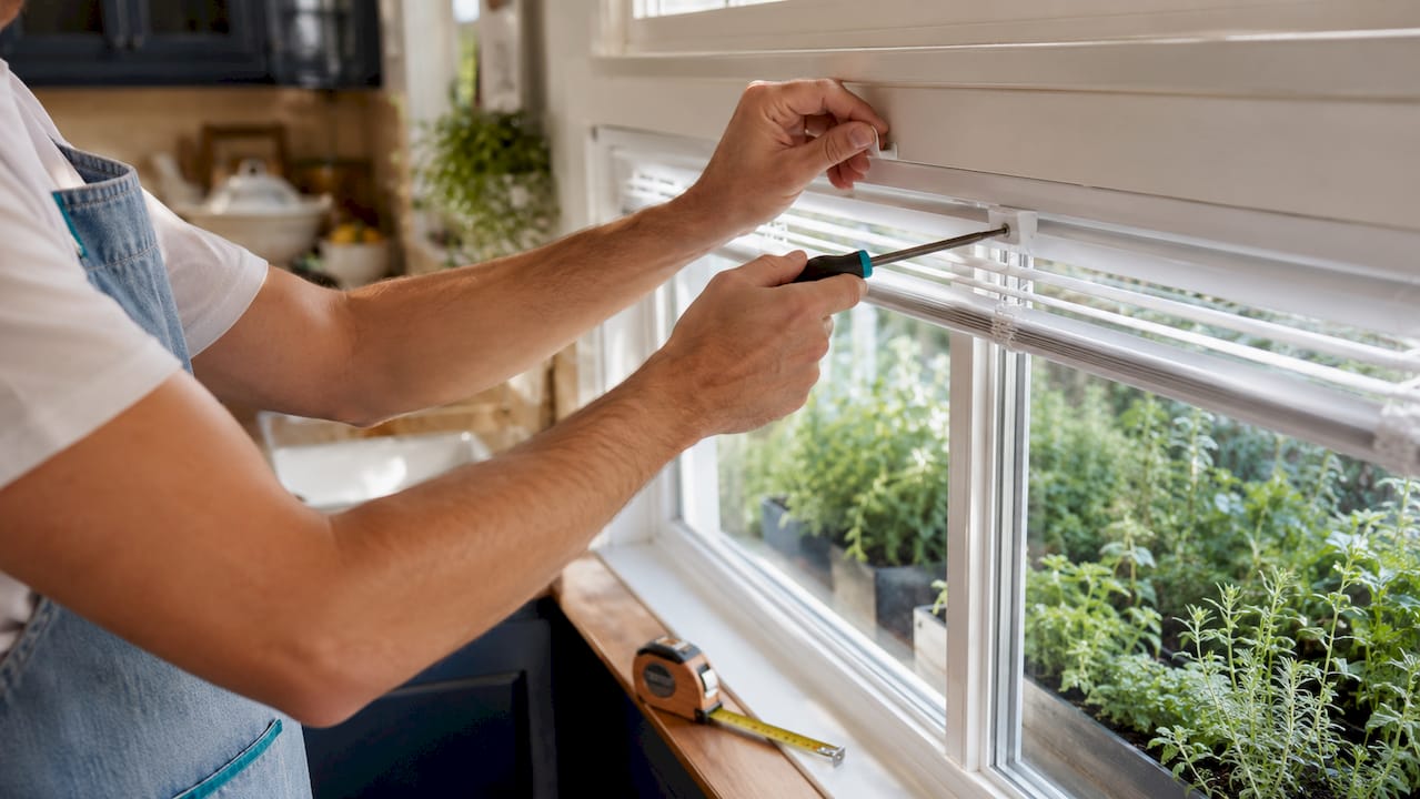Hands installing cordless vinyl mini blinds