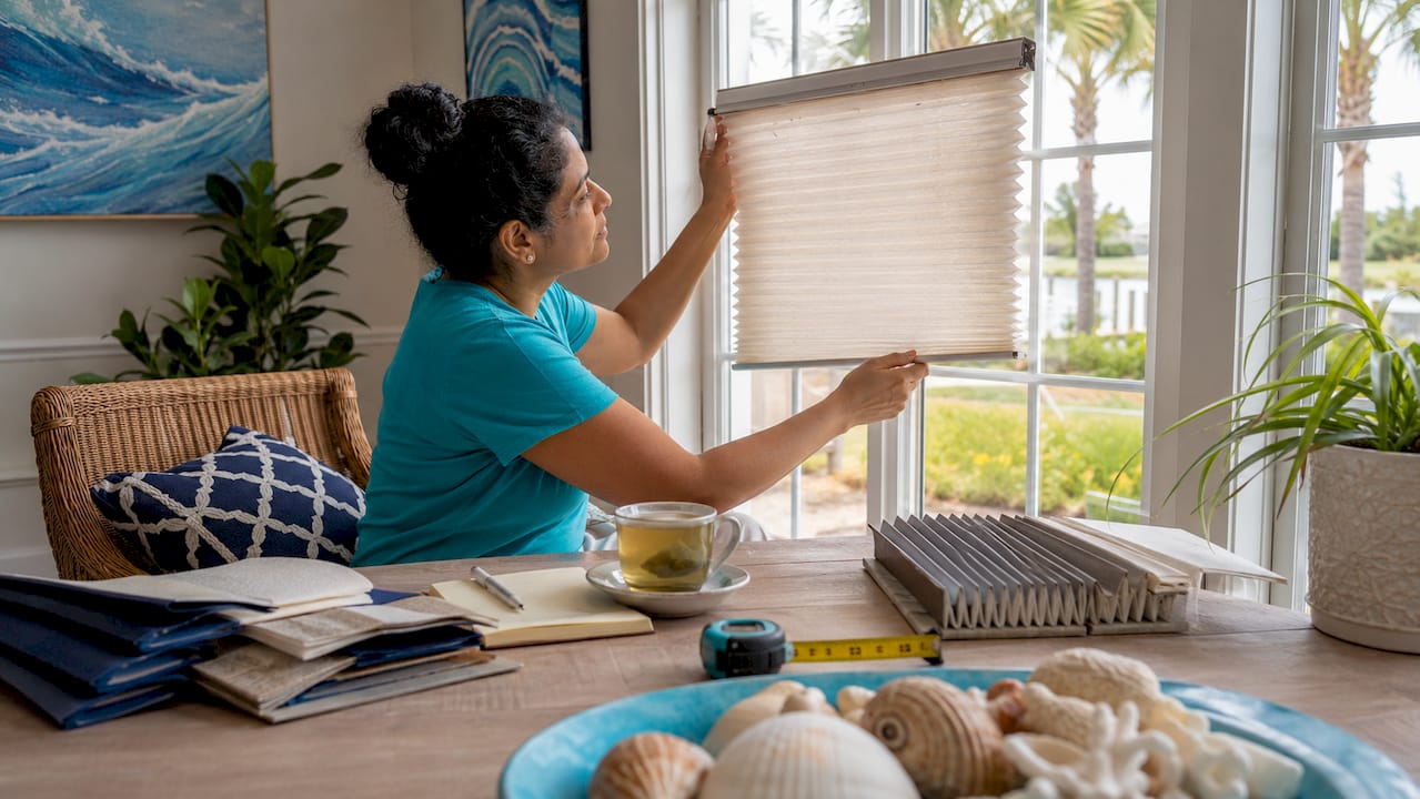 Woman testing blind sample against bathroom window indoors