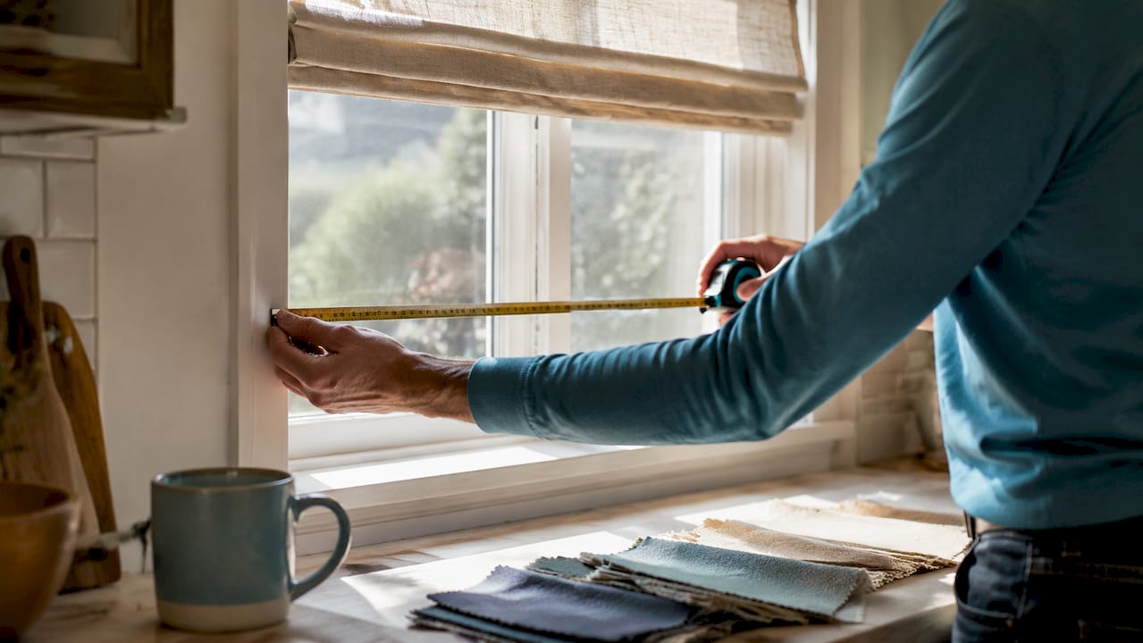 Hands measuring standard window frame with tape measure