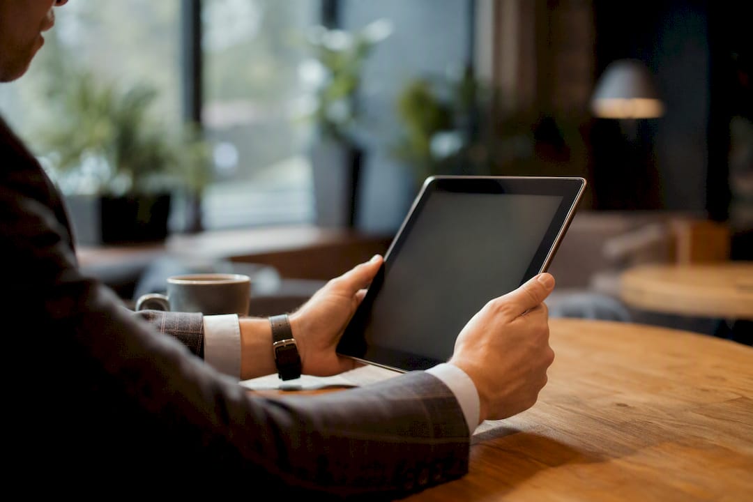 Hände halten ein Tablet und prüfen sorgfältig Vertragsbedingungen