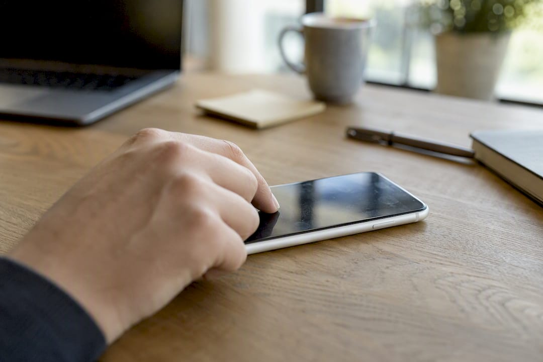 Hand, die während eines Terminplanungs-Chats auf ein Smartphone tippt