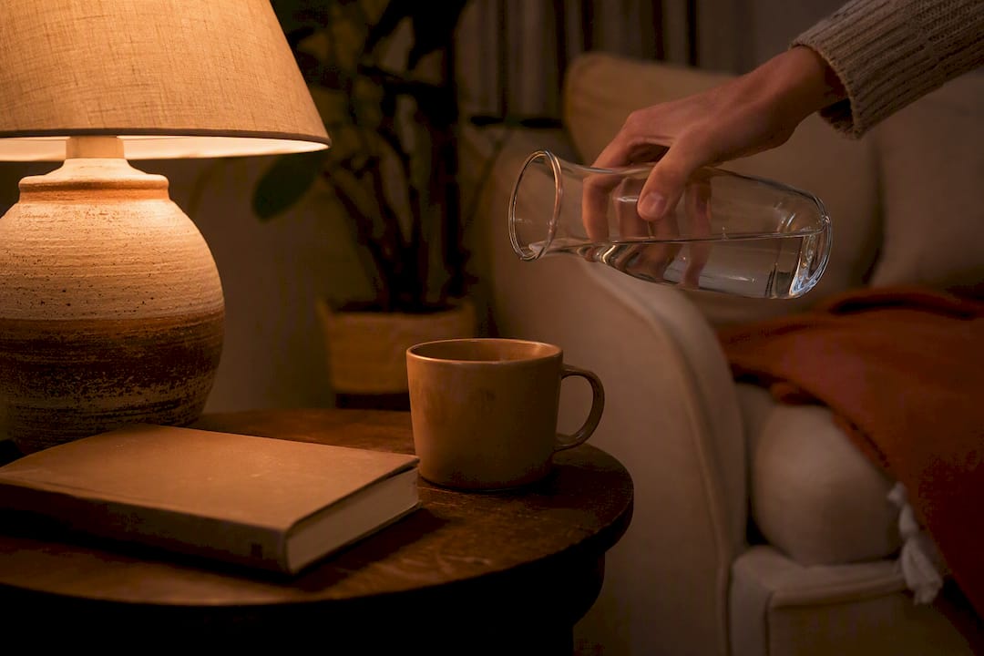 Hand refilling water mug on bedside table